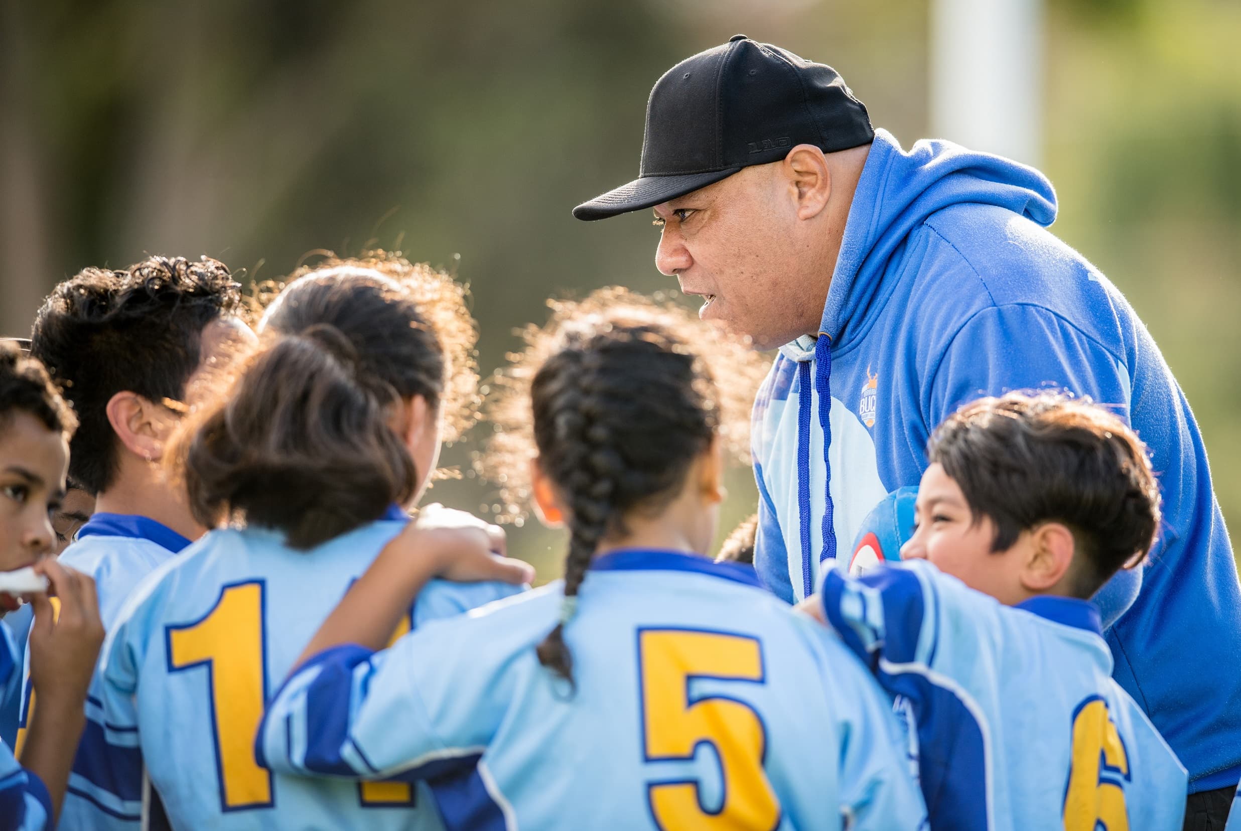 Volunteer coach speaking with children 